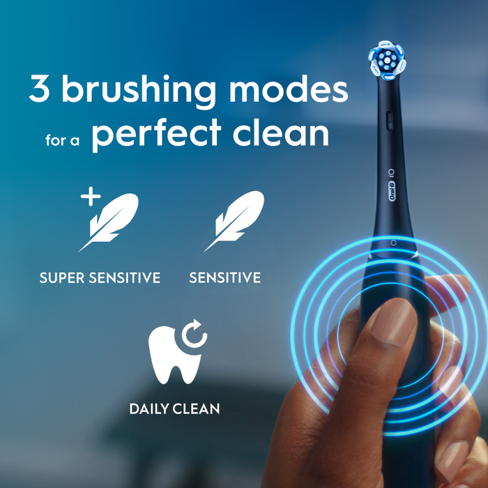 Oral-B iO2 Night Black electric toothbrush held in hand on blue background, text reads "3 brushing modes: Super Sensitive, Sensitive, Daily Clean"