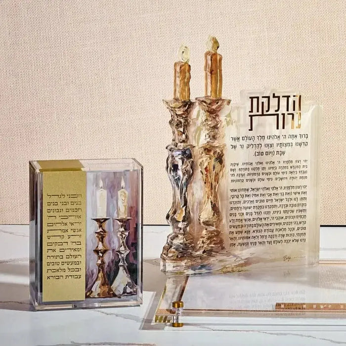 Vezakeini painted tzedakah box with decorative Jewish ritual design and candle holders, displayed with matching Shabbat candle-lighting items on white surface.