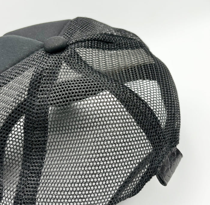 Rear view of black alligator trucker hat showing breathable mesh back and black alligator leather tab