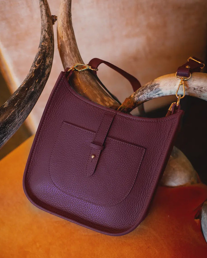 Purple leather bag on a textured surface with antlers in the background
