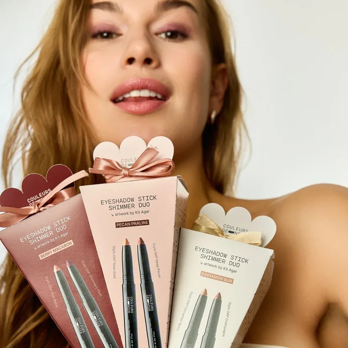 Woman holding Coulure eyeshadow stick products with a neutral background