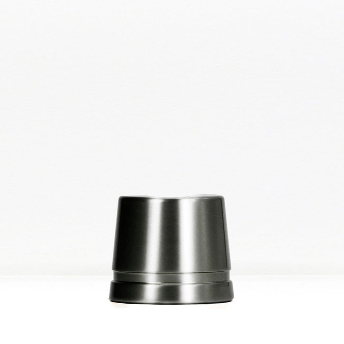 Dark gunmetal safety razor stand on a white surface.