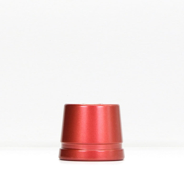 Red metal safety razor stand resting on a white surface