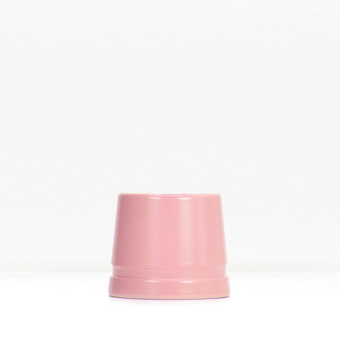 Soft pink metal safety razor stand resting on a white surface